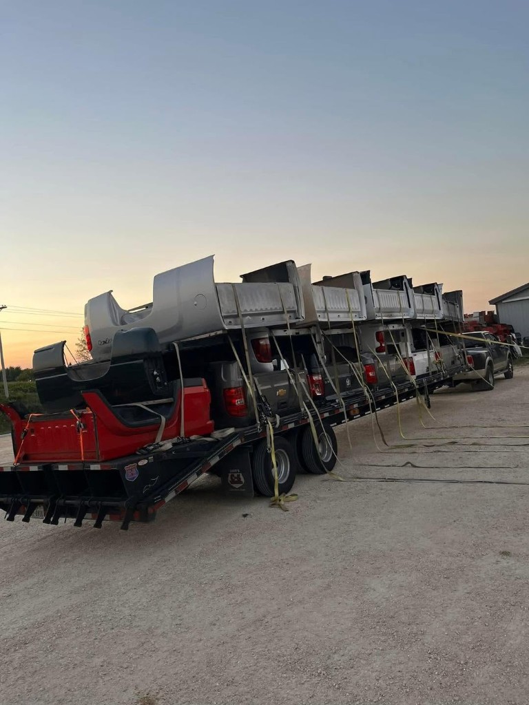 Pickup truck beds secured to a gooseneck trailer near sunset
