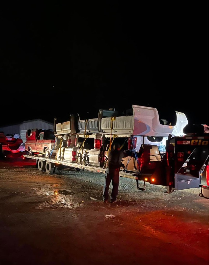 Truck beds being secured to a trailer during an evening load