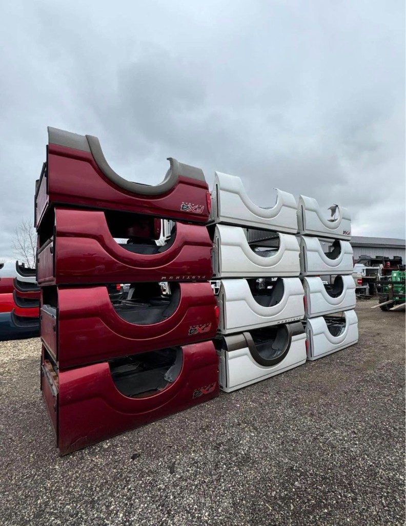Red and white pickup truck beds stacked in organized columns