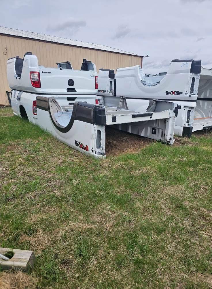 White pickup truck beds grouped beside a building