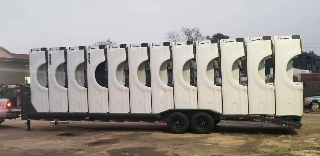White pickup truck tailgates secured upright on a large trailer